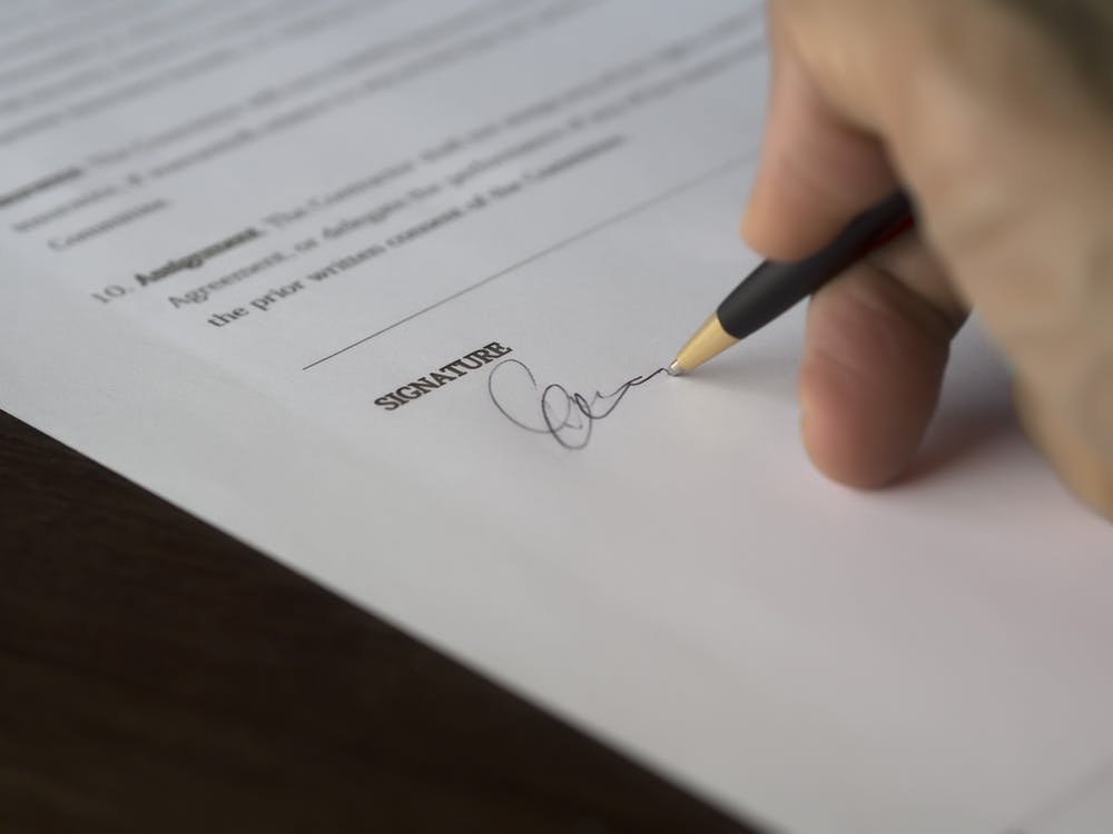 Person signing his signature on a document